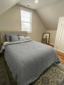 - une chambre avec un lit doté d'une couette grise et d'une fenêtre dans l'établissement Stunning and Beautiful 4 beds, 3 bath house located in Quincy near Quincy Adam RED LINE transit, à Quincy