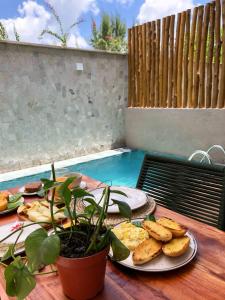 a table with plates of food and a potted plant at Refúgio a Poucos Passos do Mar l Milagres Hospedagens in Pôrto de Pedras