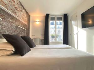 パリにあるベストウエスタン ホテル ル モンパルナスのレンガの壁のベッドルーム1室(白い大型ベッド1台付)