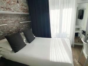 een slaapkamer met een wit bed en een bakstenen muur bij Best Western Hotel Le Montparnasse in Parijs