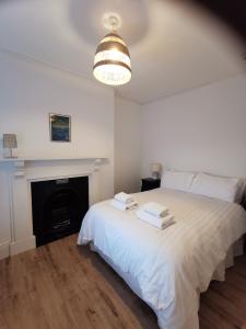 a bedroom with a white bed and a fireplace at Lovely Seafront 2 bed flat in Aberystwyth in Aberystwyth