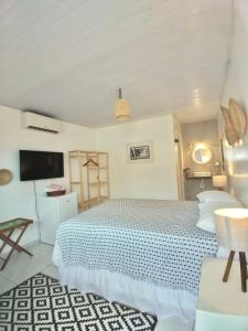 a white bedroom with a bed and a tv at Maré suites in Fernando de Noronha