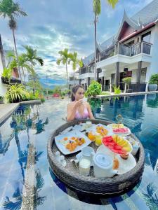 a woman sitting in a pool with a tray of food at Baan Yin Dee Boutique Resort Phuket - SHA Plus in Patong Beach