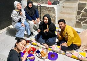 Eine Gruppe von Menschen, die an einem Tisch sitzen und Essen essen. in der Unterkunft Bumina EENK 