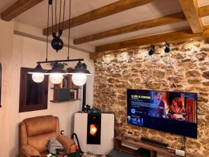 a living room with a tv on a stone wall at Cortijo Rodeo. Alojamiento Rural in Carcabuey +17 photos