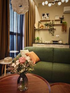 - un salon avec un canapé vert et un vase fleuri dans l'établissement "CAT THEME" 2 Bedrooms at Jelutong, Urban Suites, à Jelutong