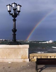a street light next to a bench and a rainbow at Dimora Nalu in Bari