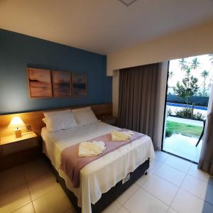 um quarto com uma cama e uma grande janela em Mana Beach Experience Muro Alto 13 C Térreo em Porto de Galinhas