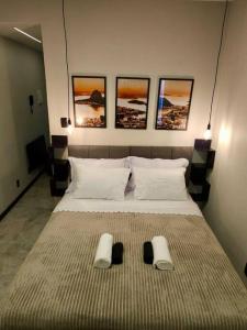 a bedroom with a large bed with three pictures on the wall at Apartamento 1 quarto em Copacabana in Rio de Janeiro
