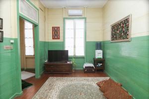 a living room with green walls and a flat screen tv at Rumah Nizar (next to Ngarai Sianok) in Bukittinggi