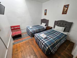 a room with two beds and a chair in it at Cusco el Conquistador in Cusco