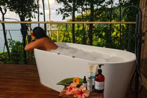 un uomo seduto in una vasca da bagno su un ponte di SCP Corcovado Wilderness Lodge a San Pedrillo