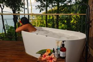 a man sitting in a bath tub on a deck at SCP Corcovado Wilderness Lodge in San Pedrillo