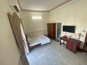 Schlafzimmer mit einem Bett, einem Schreibtisch und einem TV in der Unterkunft Magnolia Hotel Cam Ranh in Cam Ranh