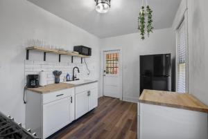 uma cozinha com armários brancos e um frigorífico preto em Housepitality - City View Loft - German Village em Columbus