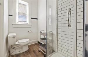 a white bathroom with a toilet and a shower at Housepitality - City View Loft - German Village in Columbus