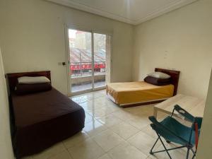 a room with two beds and a chair and a window at Casablanca Geusthouse in Casablanca