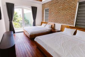 dwa łóżka w pokoju z ceglaną ścianą w obiekcie Đại Nam Villa w mieście Buôn Ma Thuột