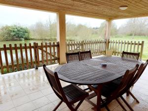 - une table et des chaises en bois sur une terrasse couverte dans l'établissement Gîte Saint-Mars-sur-la-Futaie, 4 pièces, 6 personnes - FR-1-600-94, à Saint-Mars-sur-la-Futaie