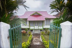 una casa con techo rosa y puerta en Rumah Nizar (next to Ngarai Sianok) en Bukittinggi