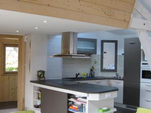 a kitchen with white cabinets and a black counter top at Maison lumineuse avec sauna, terrasse sud, proche Gérardmer, animaux acceptés - FR-1-589-369 in Gérardmer