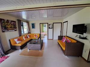 a living room with couches and a flat screen tv at Fare Mama Rota - au bord de l'océan in Taputapuapea