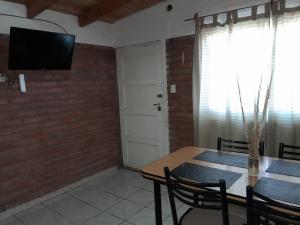 a dining room with a table and a television on a brick wall at El Pasaje in Malargüe