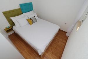 a small bedroom with a bed with white sheets and pillows at Family friendly house with a swimming pool Duge Njive, Zagora - 22311 in Vrgorac +4 photos