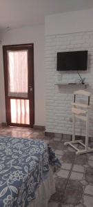 Habitación con TV en la pared y silla en SUITE A&F Habitación con baño privado en San Fernando del Valle de Catamarca