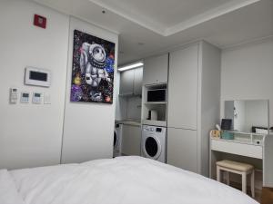 a white bedroom with a bed and a kitchen at Sokcho Summitbay 1705 "Panoramic Ocean View" in Sokcho