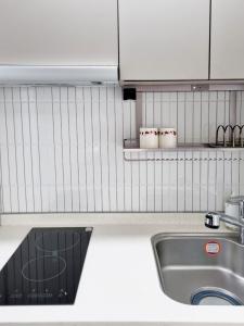a kitchen with a sink and a white tiled wall at Sokcho Summitbay 1704 "Ocean View" in Sokcho