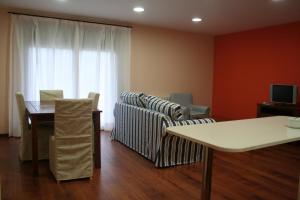 sala de estar con sofá, mesa y TV en Apartaments Tarrega Lagranja, en Tàrrega