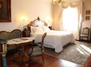 Schlafzimmer mit einem Bett, einem Tisch und einem Fenster in der Unterkunft Hotel Museo Palacio de San Agustin in San Luis Potosí