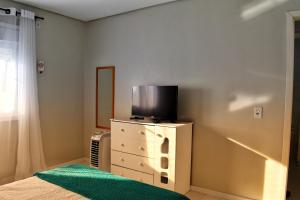 una camera da letto con TV sopra un comò di Apartamento da Júlio a São Francisco de Paula