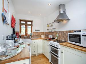 a kitchen with white cabinets and a microwave at Candles Cottage in Cubert