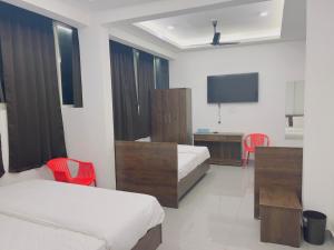 een hotelkamer met 2 bedden en een televisie bij AROMA INN in Kalpatta