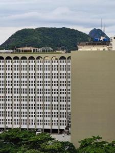 a large white building with a mountain in the background at A uma quadra da praia de Copacabana in Rio de Janeiro