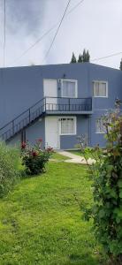 a large blue house with a lawn in front of it at Departamentos MAWER in El Calafate