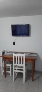 einen Tisch und eine Bank mit einem TV an der Wand in der Unterkunft Departamento MAWER in El Calafate