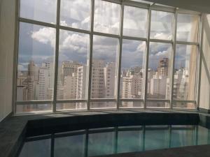 uma grande janela com vista para uma cidade em Flat Ibirapuera Jardins SP com garagem inclusa! em São Paulo