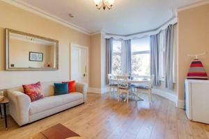 a living room with a couch and a table at Spacious Apartment In The Heart Of Ealing Broadway in London