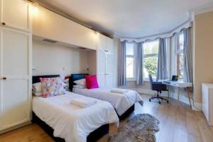 a bedroom with two beds and a desk with a computer at Spacious Apartment In The Heart Of Ealing Broadway in London