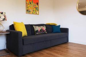 un sofá negro con almohadas coloridas en la sala de estar. en Modern one Bedroom Apartment in Ealing Common en Londres