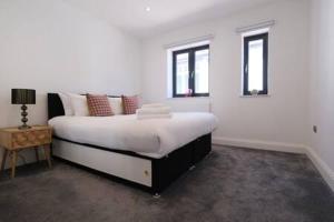 ein weißes Schlafzimmer mit einem großen Bett und einem Tisch in der Unterkunft Ealing Common Apartment with Balcony in London