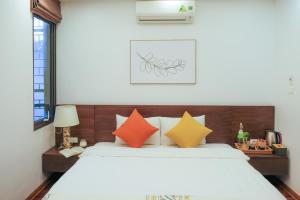 sypialnia z łóżkiem z pomarańczowymi i żółtymi poduszkami w obiekcie Luxe Paradise residence 22 Nam Ngu street w mieście Hanoi