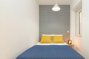 - une chambre avec un lit bleu et un oreiller jaune dans l'établissement Arroios Concept Apartments by Homing, à Lisbonne