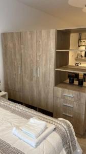 1 dormitorio con 1 cama con armarios de madera y toallas en Departamento Palermo Soho en Buenos Aires