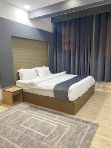 a bedroom with a large bed with a blue wall at Al Hussam Hotel Apartments in Muscat