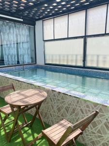 una piscina con 2 sillas y una mesa en Al Hussam Hotel Apartments, en Mascate