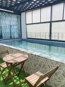 une piscine avec deux chaises et une table dans l'établissement Al Hussam Hotel Apartments, à Mascate